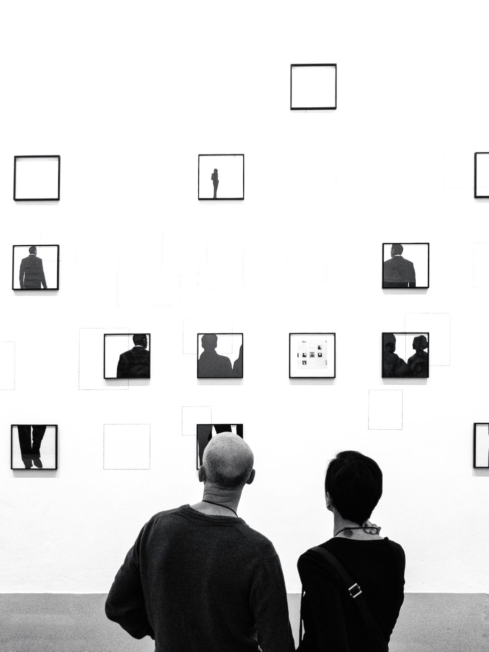 Deux visiteurs face à un mur d'œuvres