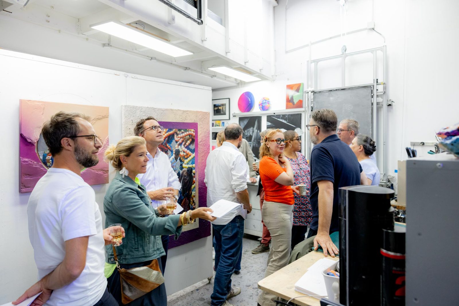 Vue d'ensemble de l'atelier : une quinzaine de participants circulent entre les toiles accrochées et les établis de travail